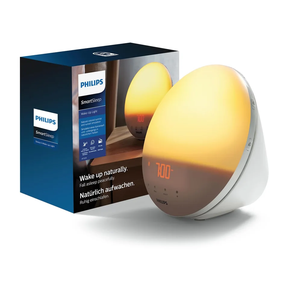 White Philips SmartSleep Wake-up Light HF3532/01 with an illuminated round front, digital clock display and retail packaging